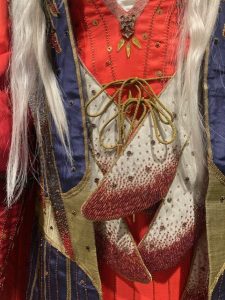 The front of the outer robe fastens by a gold cord revealing the scarlet inner robe embroidered in gold.